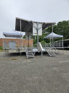 A stage with steps and canopies in the middle of an empty parking lot.